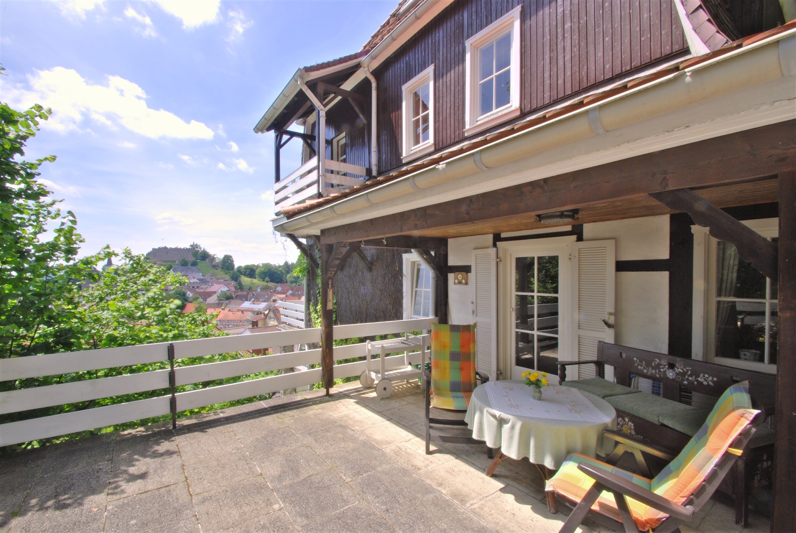 Seitlich des Hauses, die geschützt liegende Terrasse mit teilweiser Überdachung auf der Höhe des Erdgeschosses. - Oliver Reifferscheid - Immobilienmakler Darmstadt