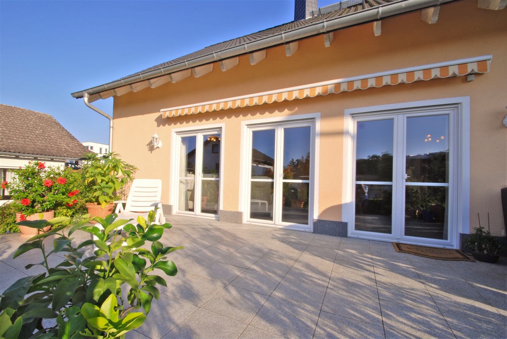 Blick von der Terrasse auf auf das quadratische Haus. Vom Wohn-, Essraum haben Sie Zugang zur Terrasse über drei doppelflüglige Fenstertüren. - Oliver Reifferscheid - Immobilienmakler Darmstadt