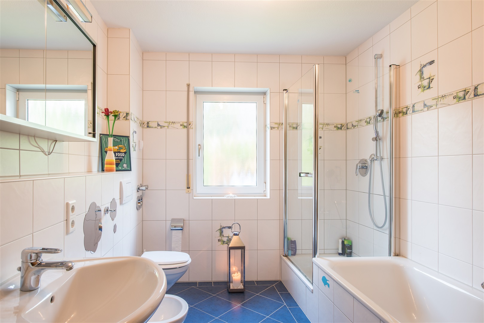 Helles und modern gefliestes Badezimmer mit Badewanne, Dusche, Waschtisch, WC und einem Bidet. Der Spiegelschrank gehört zum Angebotsumfang. - Oliver Reifferscheid - Immobilienmakler Darmstadt