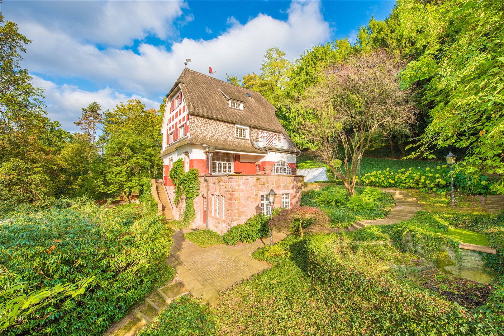 Die Südfassade mit großer Südterrasse. Im rechten unteren Bildrand die beiden Wasserbecken die durch einen Wasserüberlauf verbunden sind. Die Südterrasse wurde nachträglich von Herrn Metzendorf als Bürotrakt angebaut. Der entstandene Bereich ist hell und  - Oliver Reifferscheid - Immobilienmakler Darmstadt