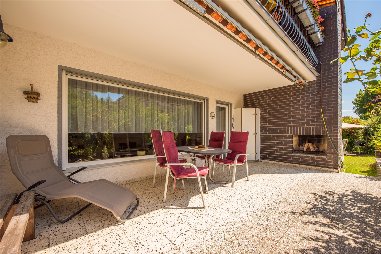 Überdachte und geschützte Westterrasse der Erdgeschosswohnung mit Außenkamin. Die Markiese ist terrassenbreit und gehört zum Angebotsumfang. - Oliver Reifferscheid - Immobilienmakler Darmstadt
