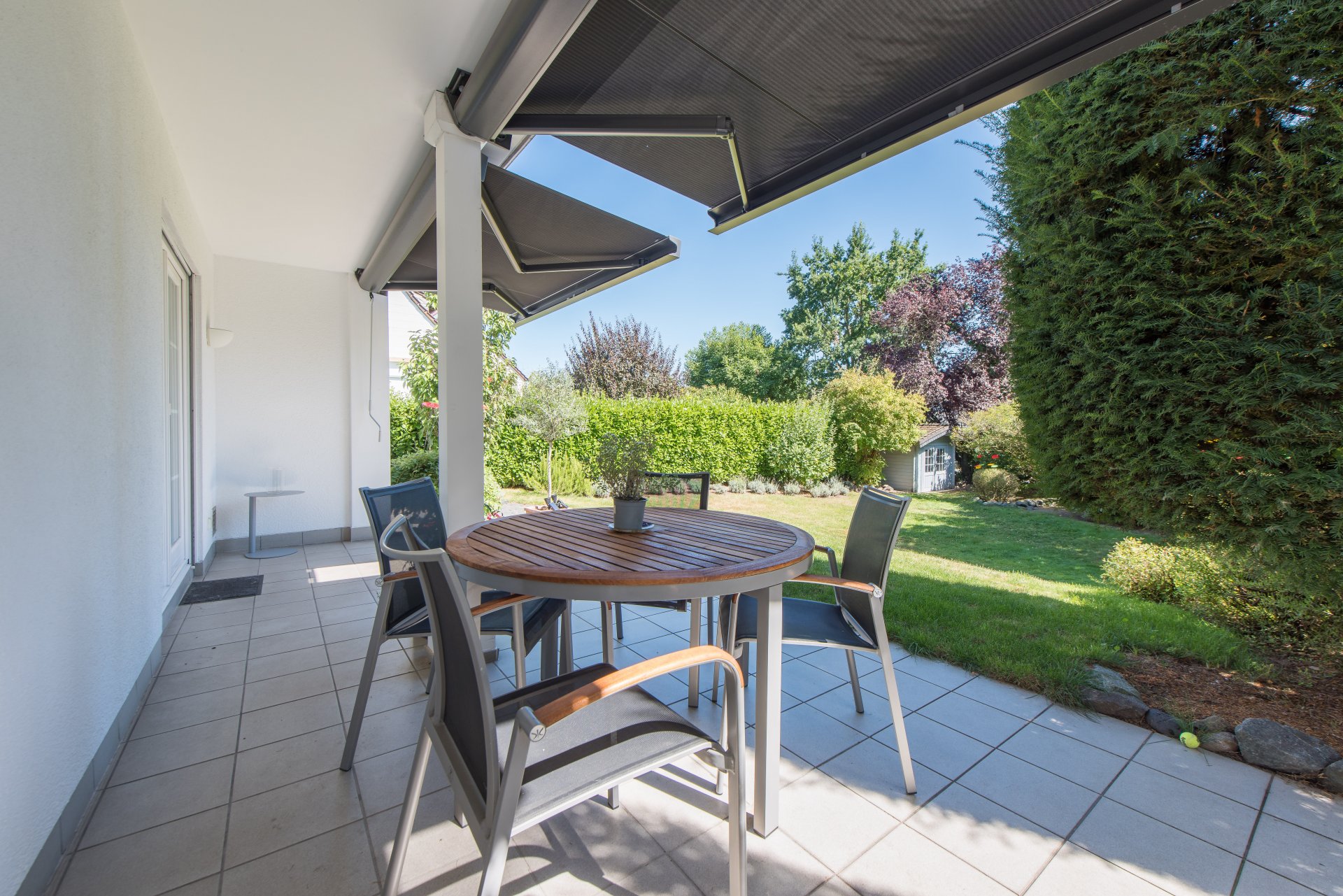 Überdachte Terrasse mit Südausrichtung zum Garten, die elektrischen Markiesen sind von ca. 2021 - Oliver Reifferscheid - Immobilienmakler Darmstadt